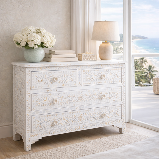 White dresser with floral patterns in a room with a view of the ocean.