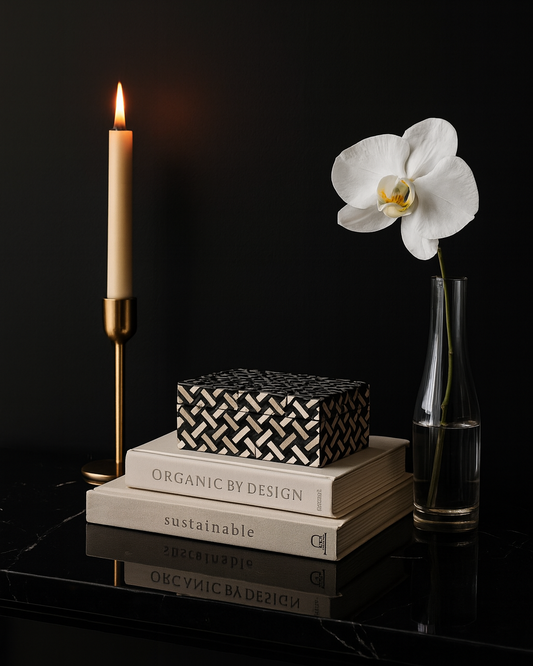 Decorative setup with books, a candle, and a white orchid on a dark surface.