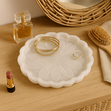 White decorative dish with gold rings, a small bottle of perfume, a brush, and lipstick on a wooden surface. White decorative dish with gold rings, a small bottle of perfume, a brush, and lipstick on a wooden surface.