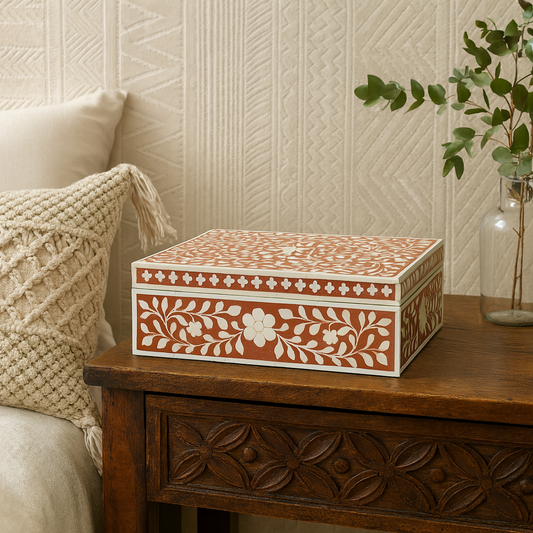 Decorative box with floral patterns on a wooden table against a textured wall.