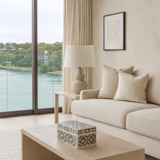 Modern living room with a couch, coffee table, and scenic view through large windows.