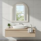 Bathroom with a wooden vanity, white sink, and decorative mirror.