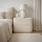 Neatly arranged bedroom with a nightstand, lamp, and bed.