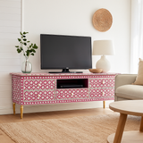 Living room with a pink patterned TV stand, television, lamp, and sofa.