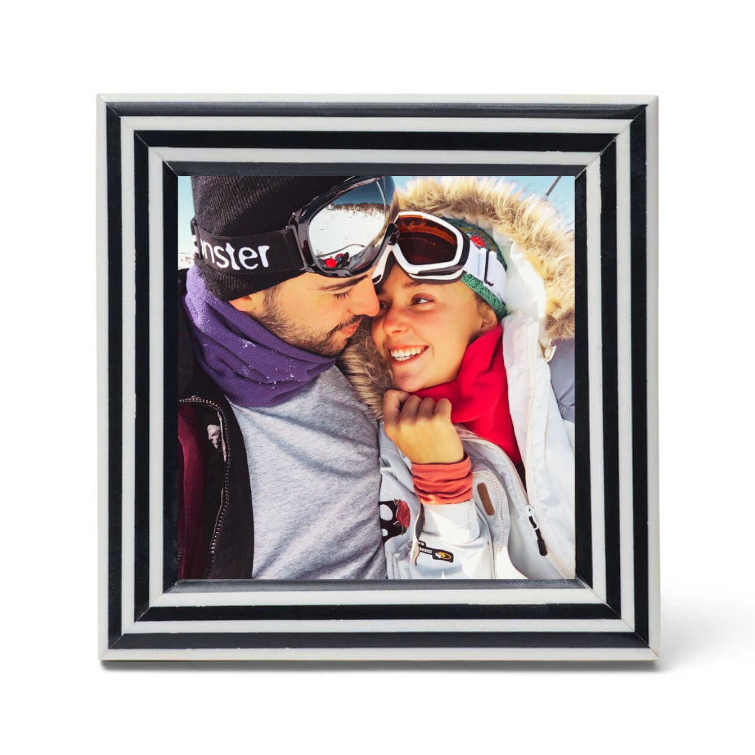 Framed photo of a couple wearing winter gear with goggles on a white background