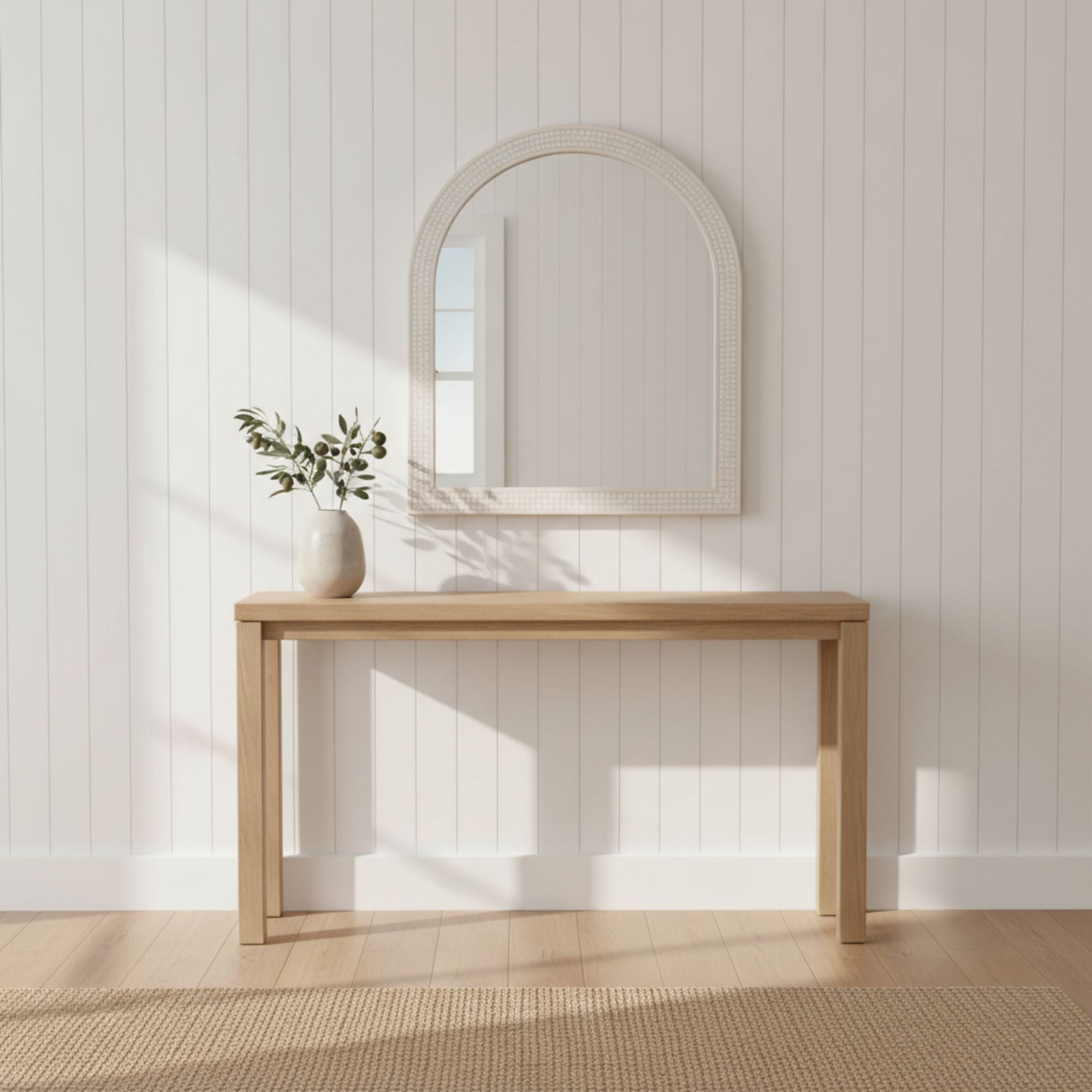 Wooden console table with a mirror and vase against a white paneled wall.