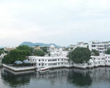 White buildings along a waterfront with trees and mountains in the background