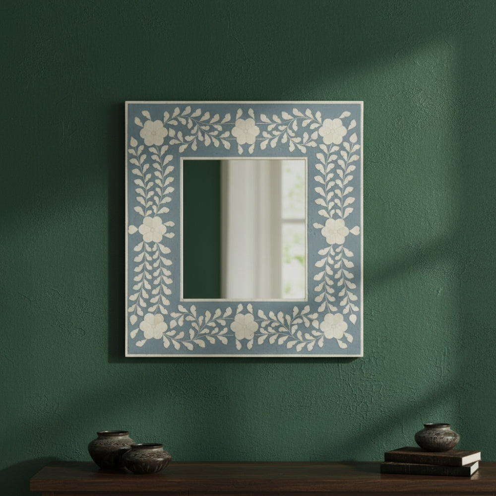 Decorative mirror with floral pattern on a green wall