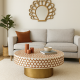 Living room with a gray sofa, patterned coffee table, and decorative mirror.
