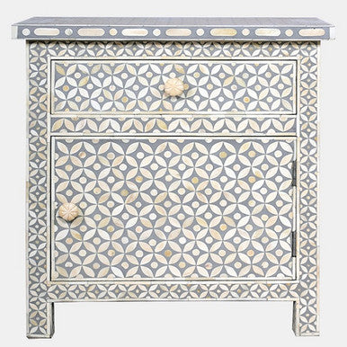 A grey bedside cabinet with bone inlay in a starburst pattern, featuring three drawers with bone handle knobs.
