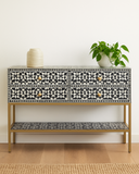 Decorative console table with black and white pattern on a wooden floor.