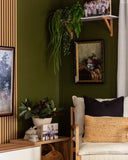 Nestled corner of a room with a green wall, a white chair with a black pillow, and decorative elements.