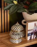 Decorative black and gold container on a wooden surface with a blurred background