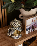 Decorative black and white patterned containers on a wooden surface with a family photo in the background.