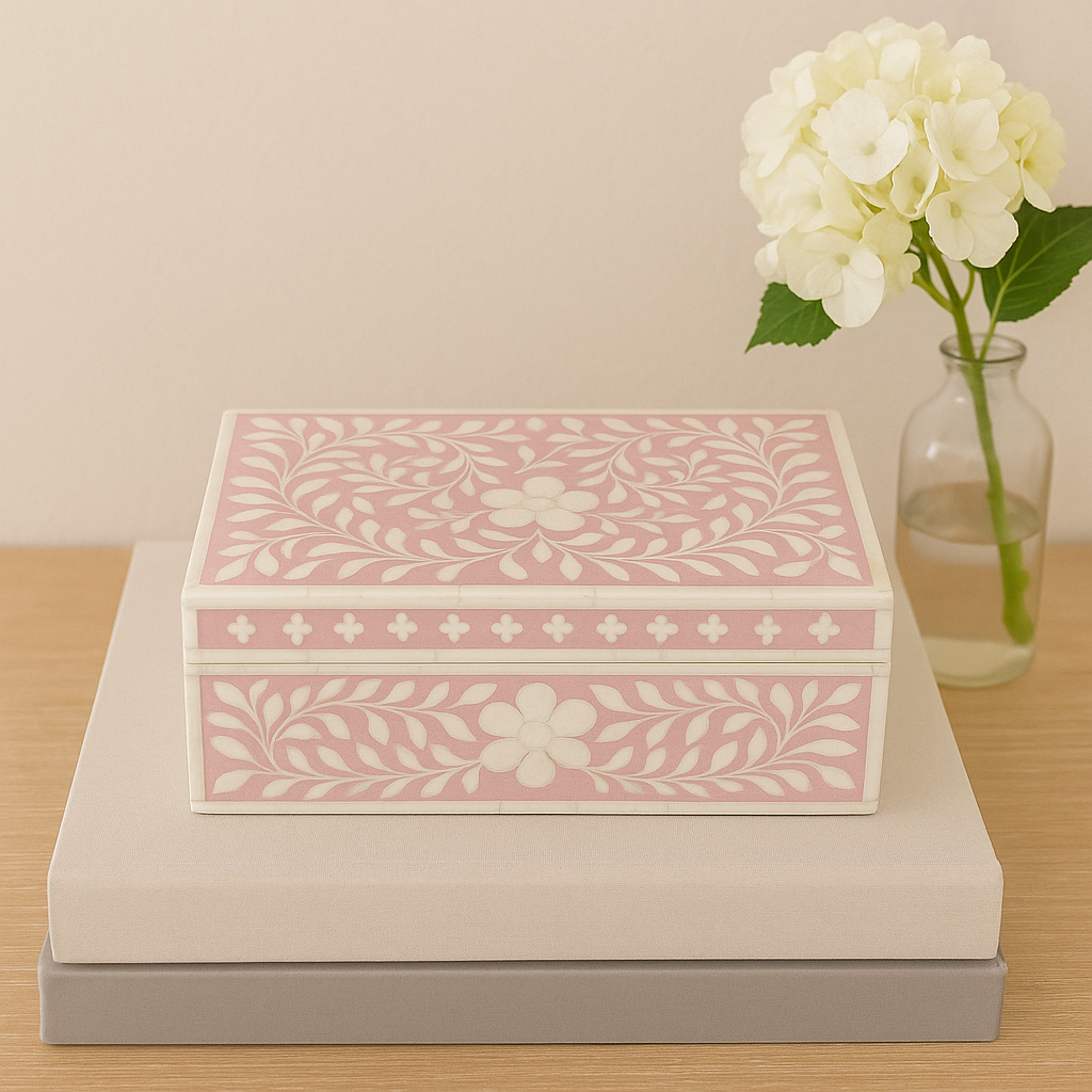 Decorative jewelry box with floral pattern on a wooden surface with a vase of flowers.