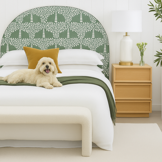 Dog lying on a bed with a green patterned headboard and wooden nightstand.