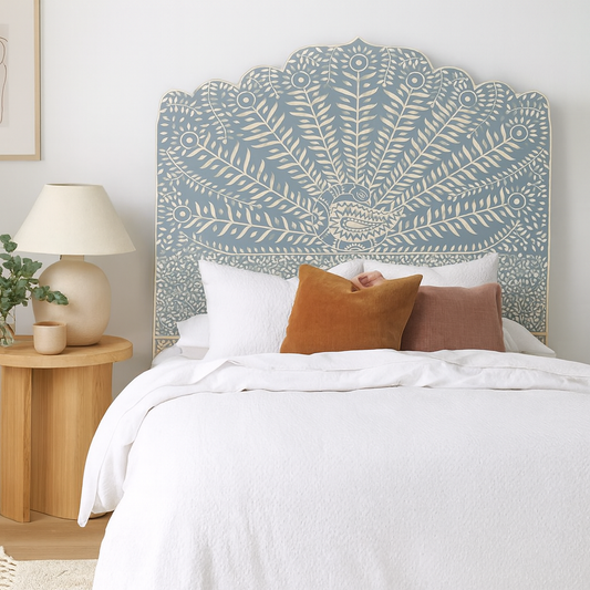 Bedroom with a decorative headboard, pillows, and a lamp on a nightstand.