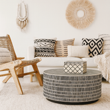 Living room with a white sofa, patterned cushions, and a round coffee table.