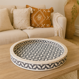 Decorative tray with geometric pattern on a wooden table in a living room setting.