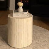 Wooden side table with books and a decorative item on top in a home setting.