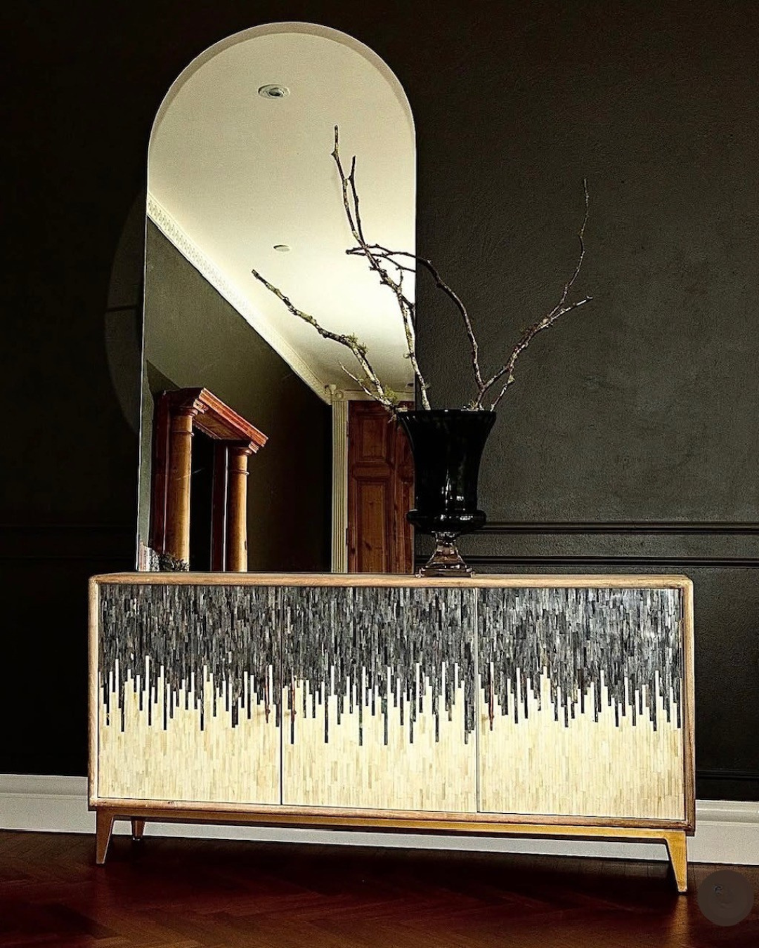 Decorative cabinet with a mirror above it in a room setting.