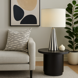 Living room with a beige sofa, black and white striped lamp, and decorative elements.
