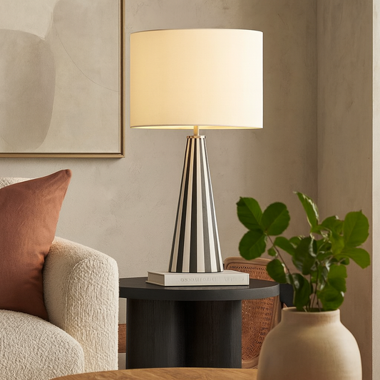 Modern lamp on a side table with a plant and sofa in a living room setting