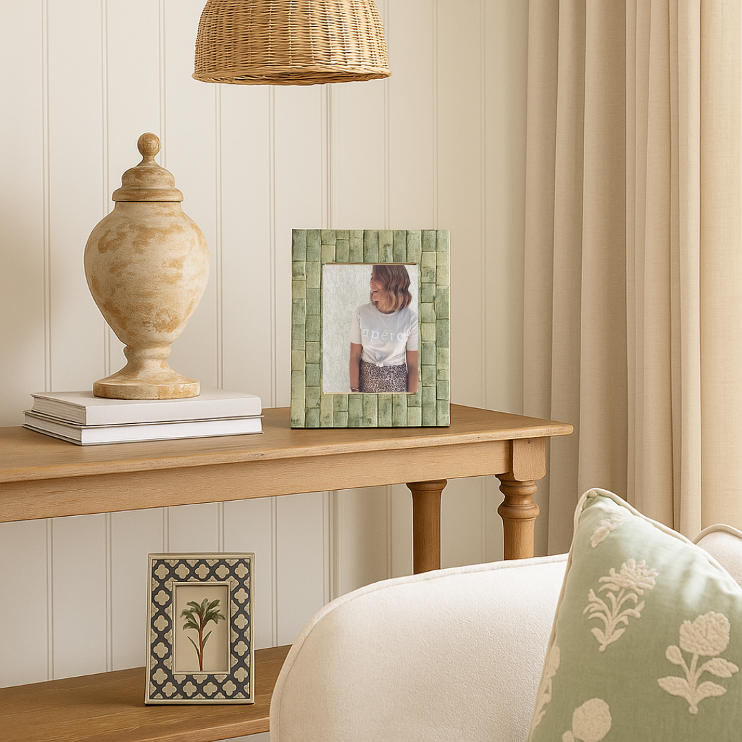 Decorative elements on a wooden table with a lamp and framed pictures in a room.
