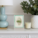 Decorative shelf with a lamp, framed picture, candle, and plant.
