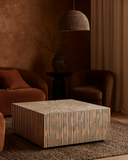 Hexagonal coffee table in a warm-toned living room with brown furniture and decor.