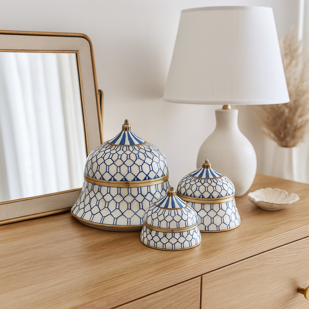 Three blue and white patterned ceramic domes on a wooden surface with a lamp and mirror in the background.