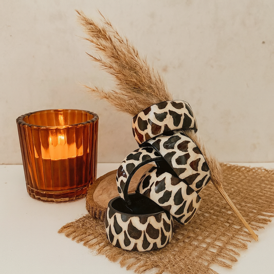 Leopard print candle holders with an orange candle and pampas grass on a neutral background