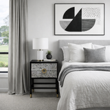 Modern bedroom with a bed, nightstand, and abstract art on the wall.