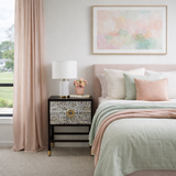Neatly made bed with pink and green bedding in a bedroom setting.