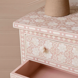 Pink jewelry box with floral patterns and an open drawer against a beige background