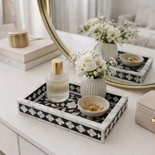 Decorative tray with a bottle, flowers, and jewelry on a vanity table.