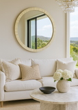 Living room with a round mirror, white sofa, and decorative elements.