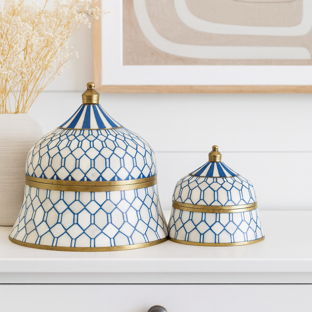 Two decorative jars with blue and white geometric patterns and gold accents on a shelf.