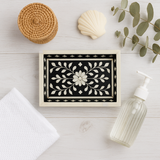 Decorative box with floral design on a white surface with a towel, soap, and plant.