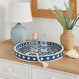 Decorative blue and white tray on a wooden surface with a lamp, candles, and plants.
