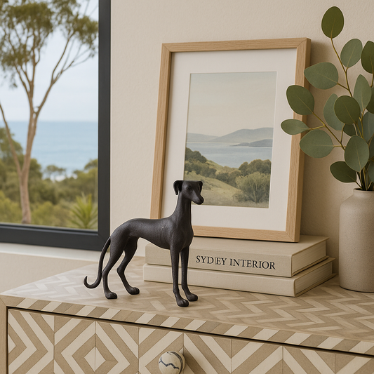 Decorative dog figure on a shelf with a framed picture and plant in the background