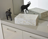 Decorative boxes with floral patterns and black elephant figurines on a reflective surface.