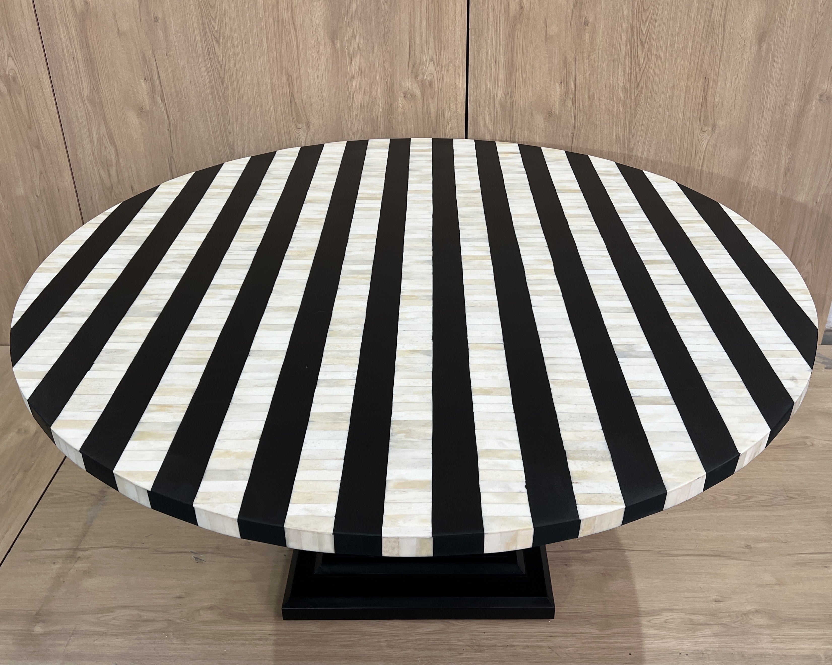 Round table with black and white striped cover on a wooden floor.