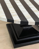 Round table with black and white striped top on a wooden floor