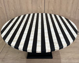Round table with black and white striped cover on a wooden floor.