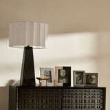 Modern table lamp with a white shade on a decorative cabinet against a beige wall.