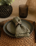 Table setting with a green napkin, plate, and glass on a woven placemat.