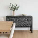 Decorative black console table with a vase and bowl against a white wall.