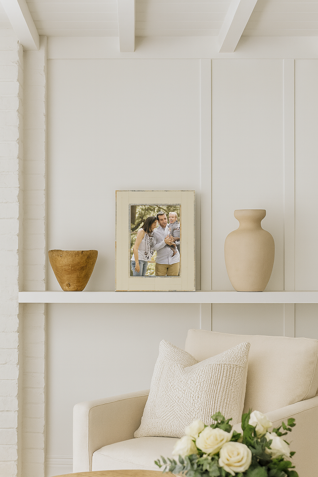 Shelving unit with decorative items including a vase, photo frame, and vase in a room with white walls and a beige sofa.