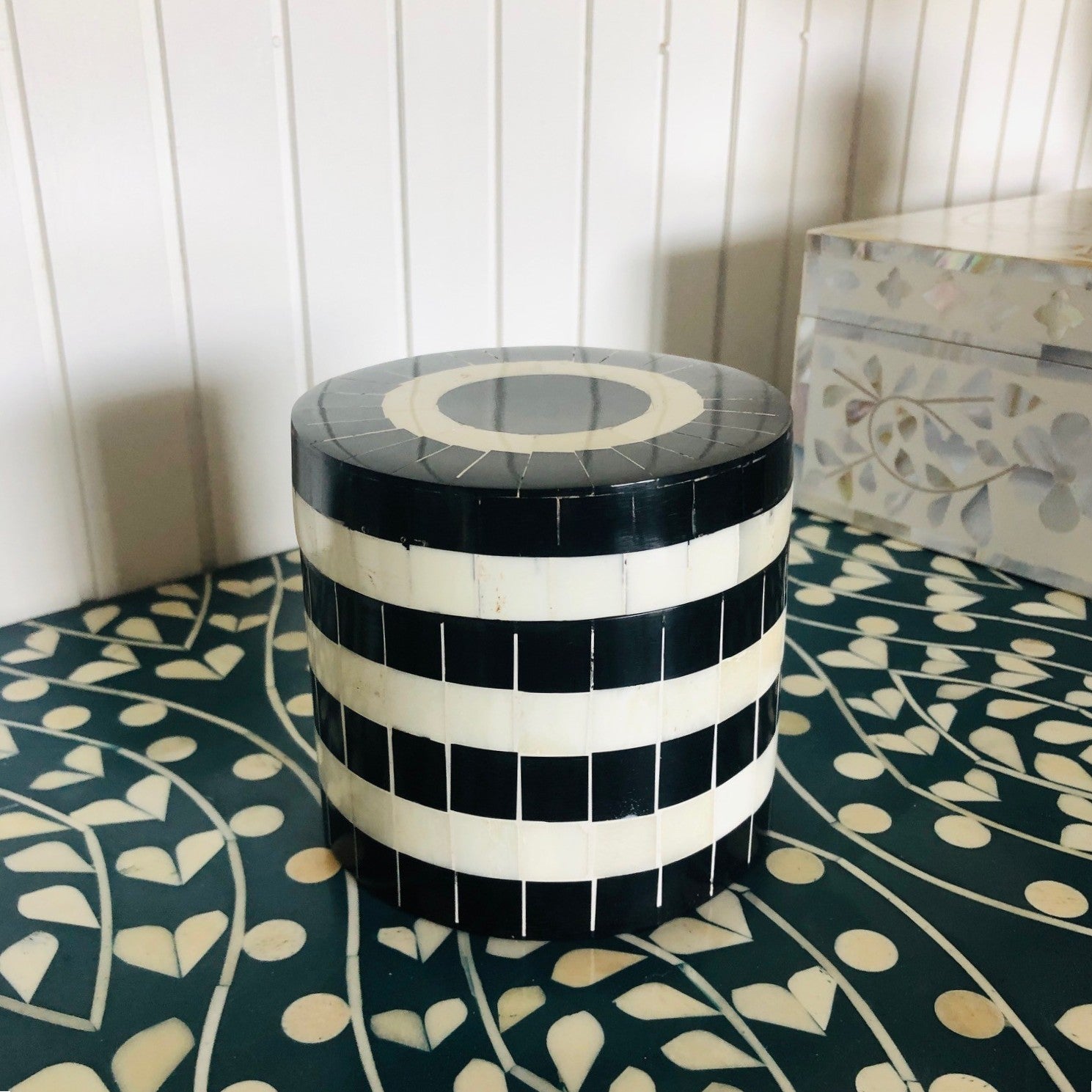 Black and white striped cylindrical stool on a patterned floor.